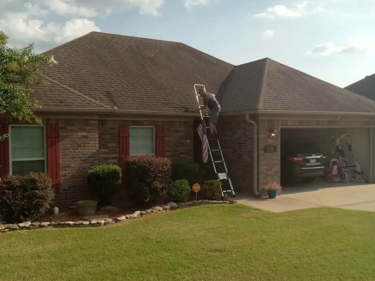 Hero Roofing crew member on a ladder at a brick ranch home in Central Arkansas — asphalt shingle roof