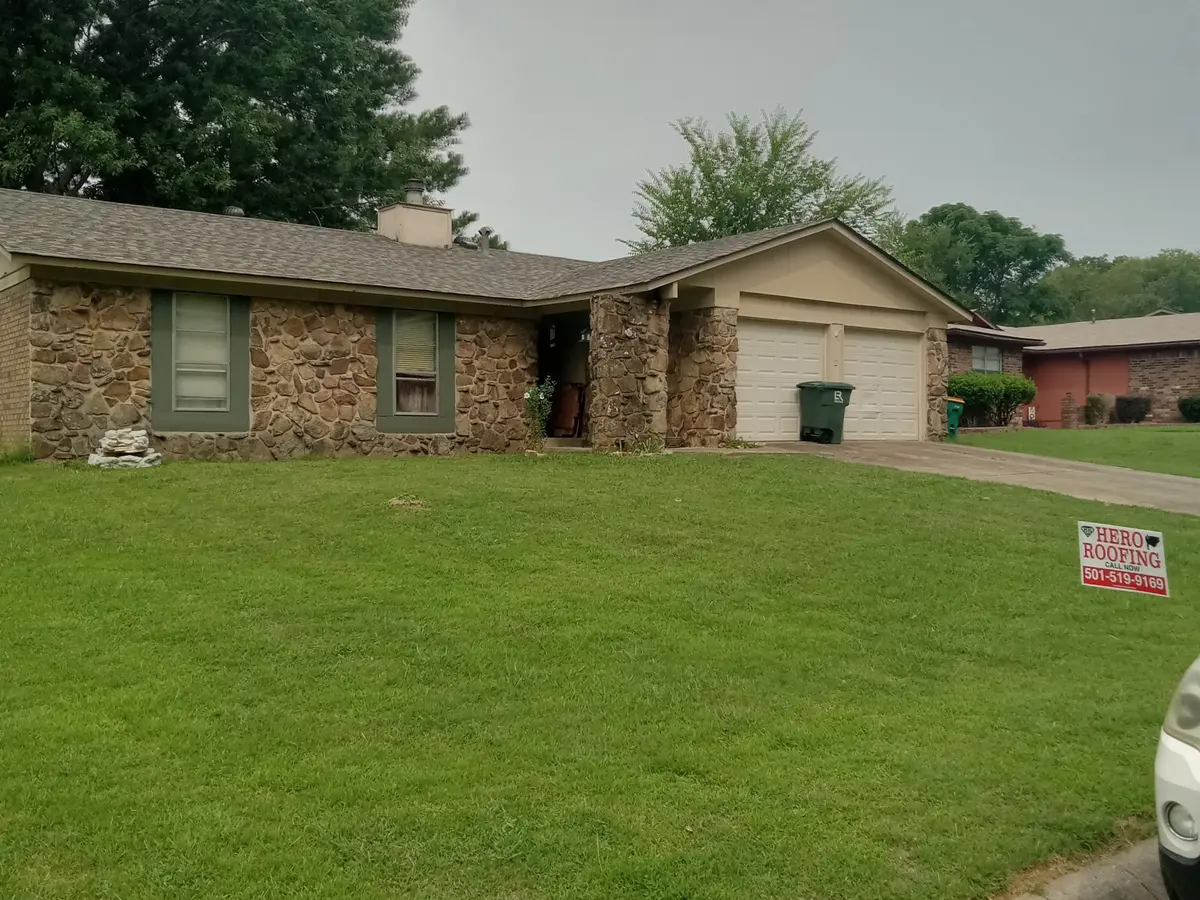 Completed asphalt shingle roof on a stone-front ranch home in Central Arkansas with a Hero Roofing yard sign