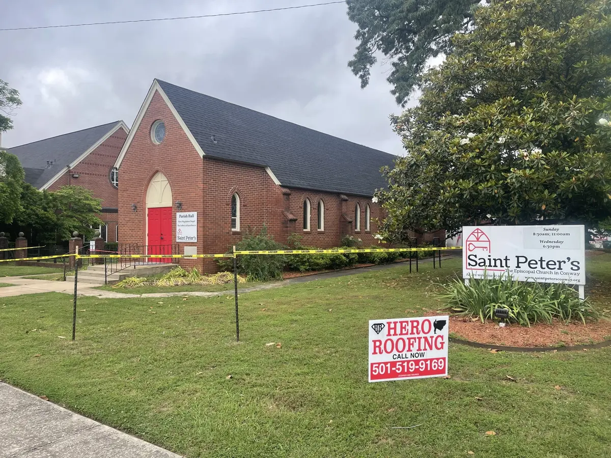 Saint Peter's Episcopal Church in Conway, AR with a new roof and a Hero Roofing yard sign out front