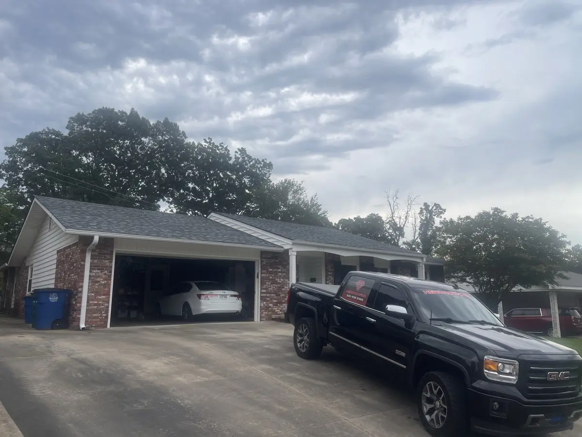 Completed roof replacement on a brick ranch home in Central Arkansas with the Hero Roofing truck in the driveway
