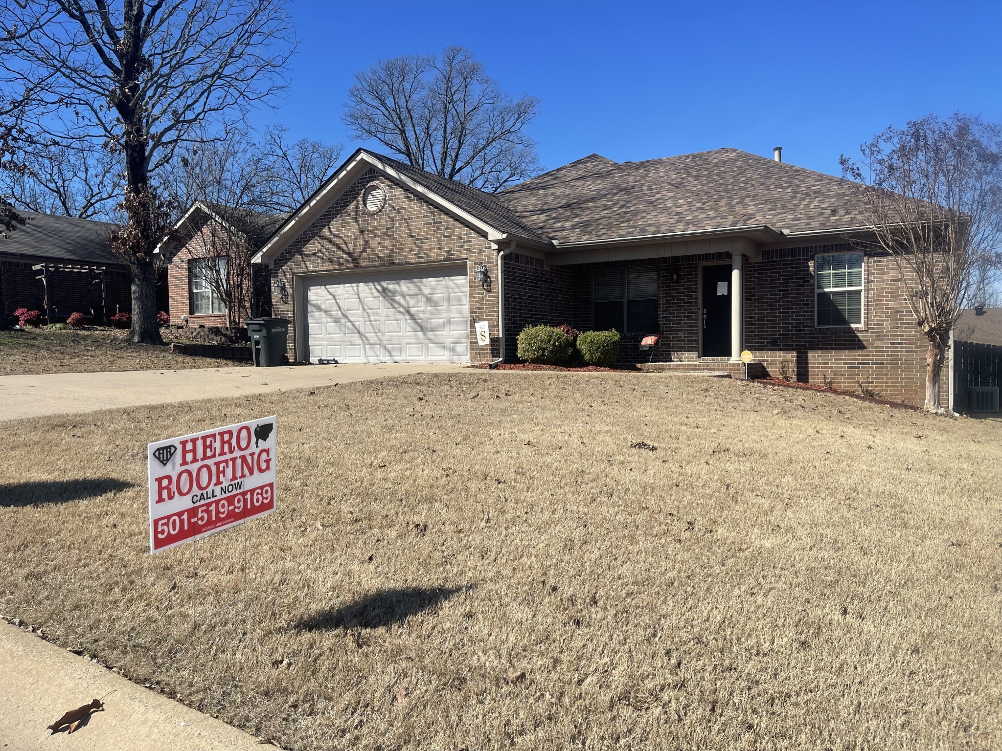 Completed asphalt shingle roof on a brick home in Central Arkansas with a Hero Roofing yard sign out front