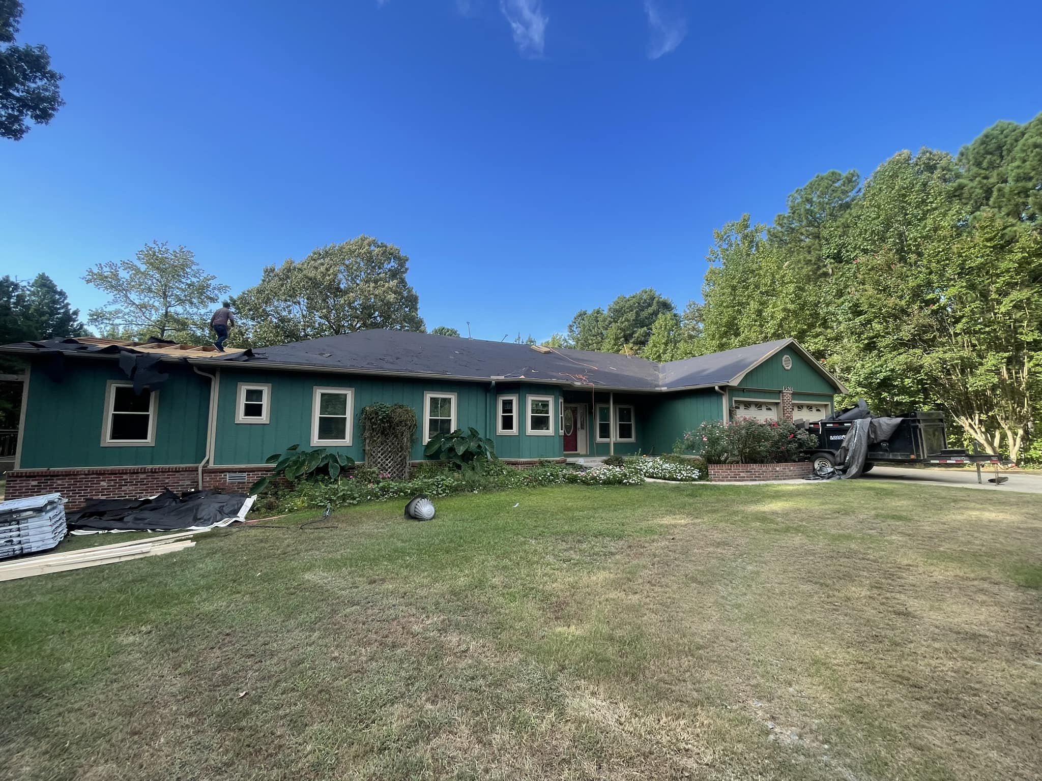 Roof replacement in progress on a green-painted ranch-style home in Central Arkansas by Hero Roofing