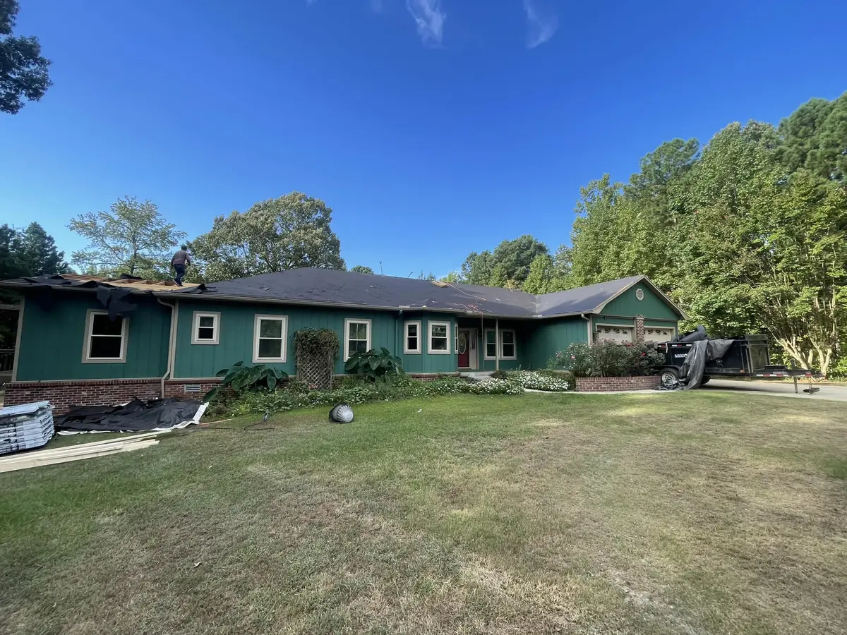 Roof replacement in progress on a green-painted ranch-style home in Central Arkansas by Hero Roofing
