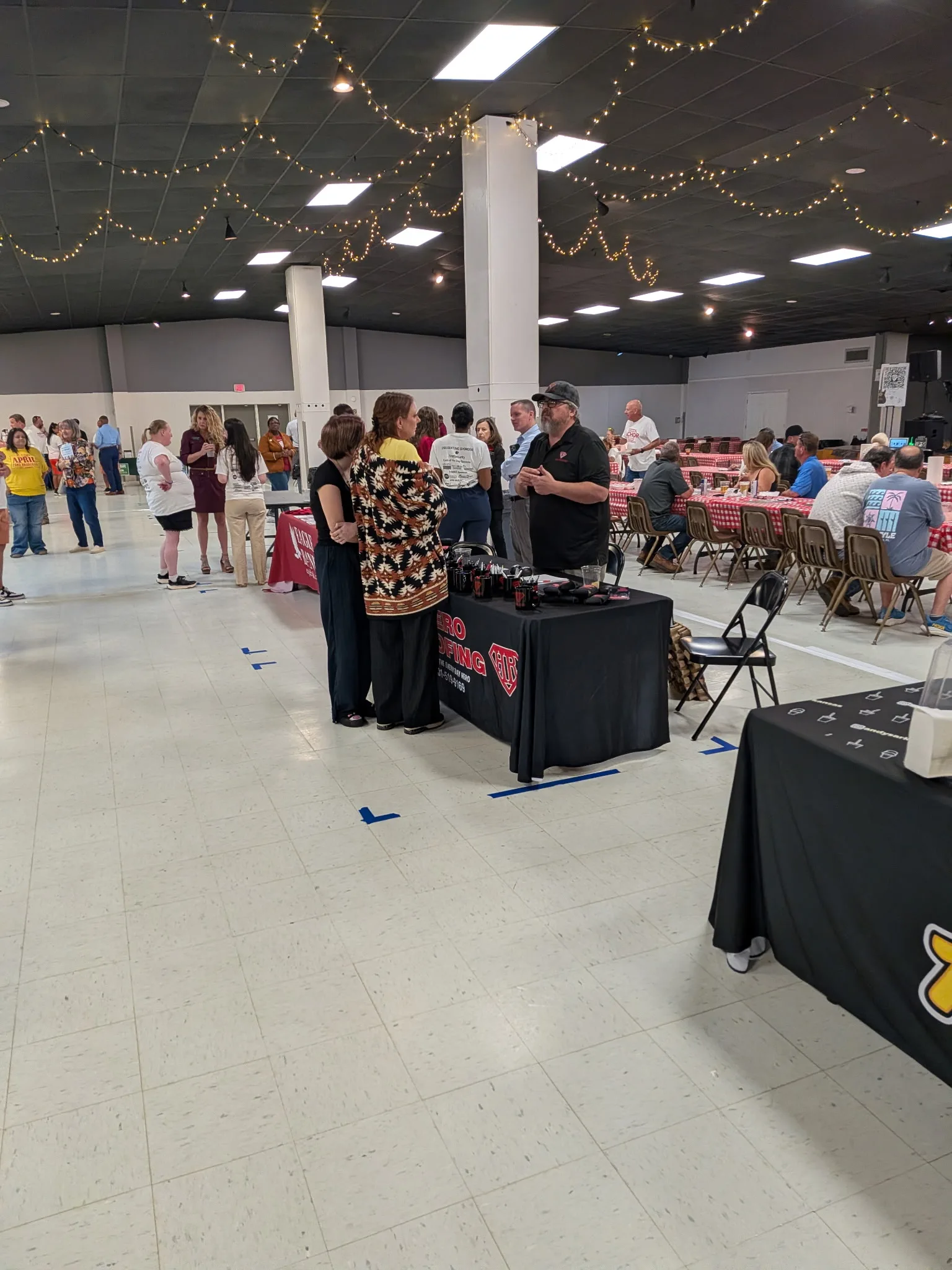 Attendees gathering around the Hero Roofing table and nearby dining tables at the Sherwood Fish Fry